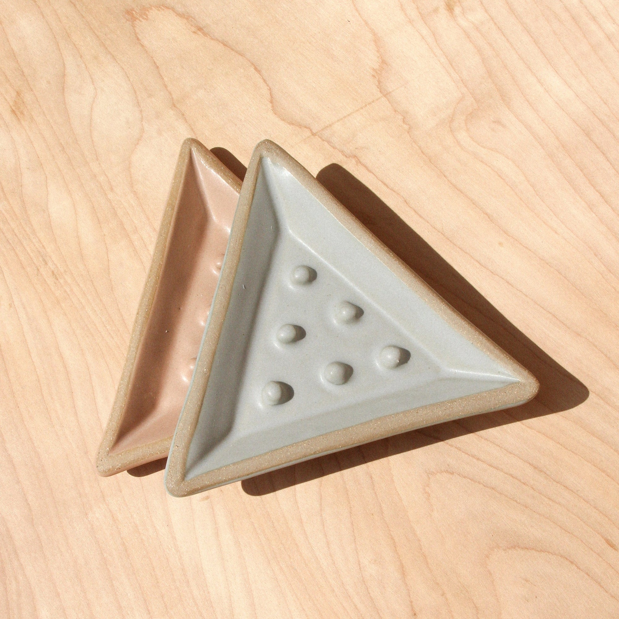 Two ceramic soap dishes against wood grain